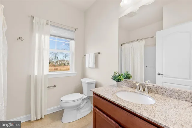 a bathroom with a granite countertop sink toilet and a mirror