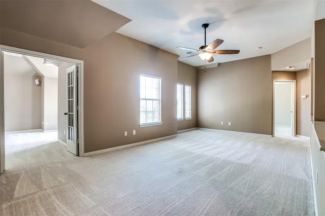 a view of an empty room with window and a ceiling fan