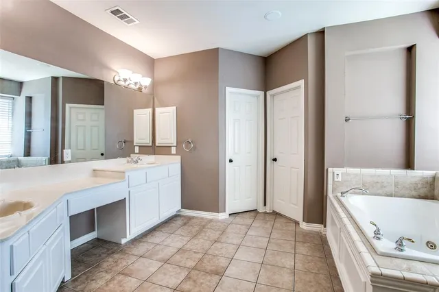 a spacious bathroom with a tub sink and mirror