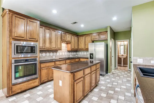 a kitchen with stainless steel appliances granite countertop a refrigerator a stove top oven and sink
