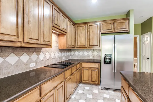 a kitchen with granite countertop stainless steel appliances a refrigerator a stove a sink and cabinets