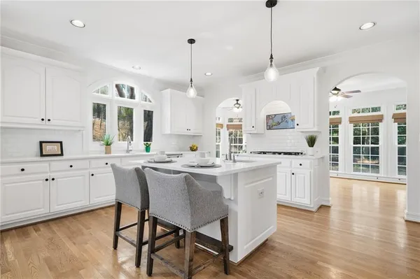 a kitchen with stainless steel appliances a stove a sink a refrigerator a center island a rug and a wooden floor