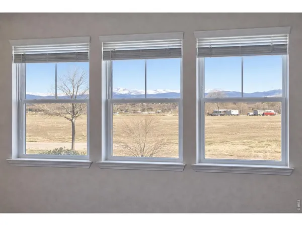 a view of an empty room with wooden floor and windows