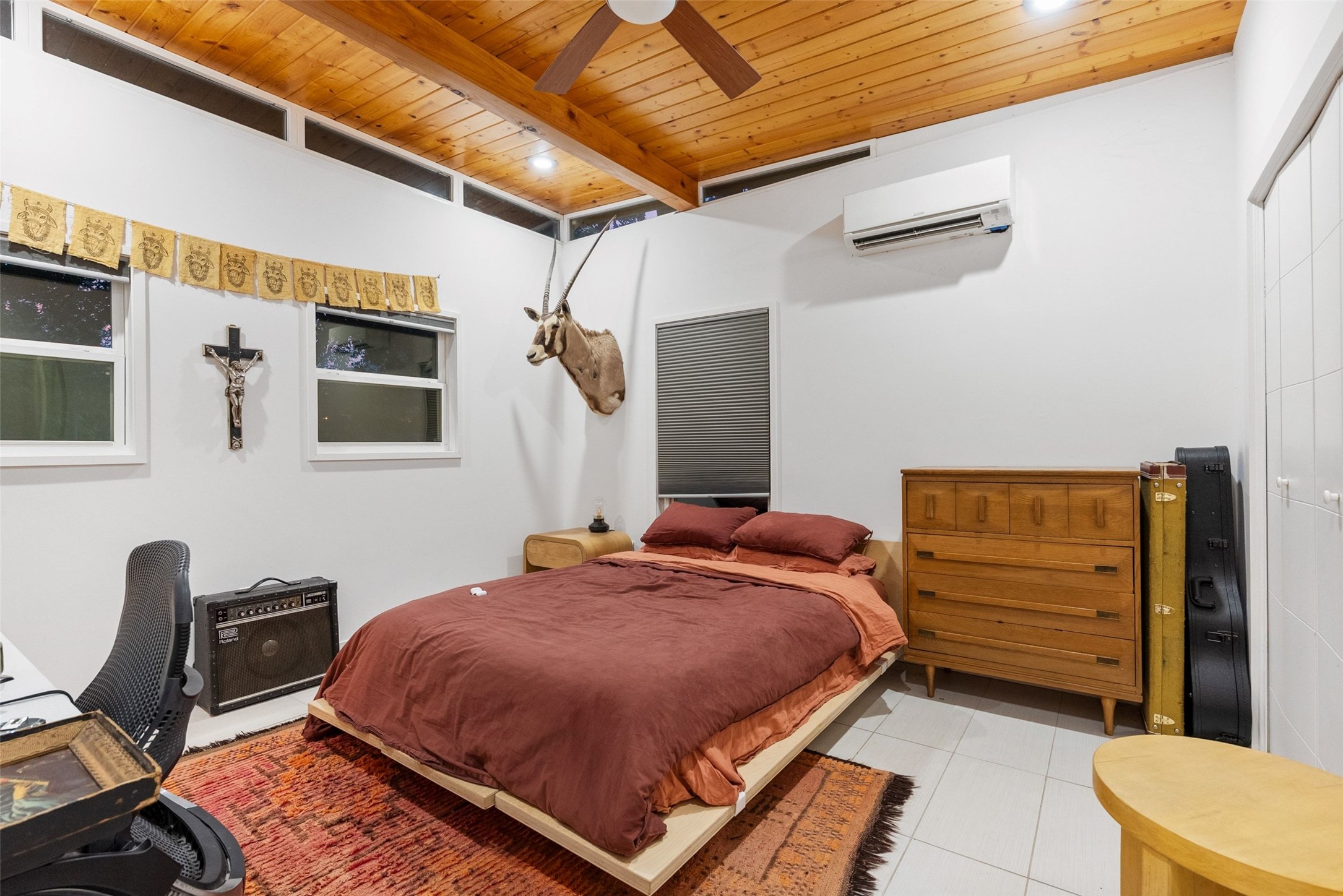 412 West Croslin Street Austin, TX 78752 - Photo 29 of 36 A vibrant area rug anchors this inviting bedroom, featuring a warm wood plank ceiling and abundant natural light.