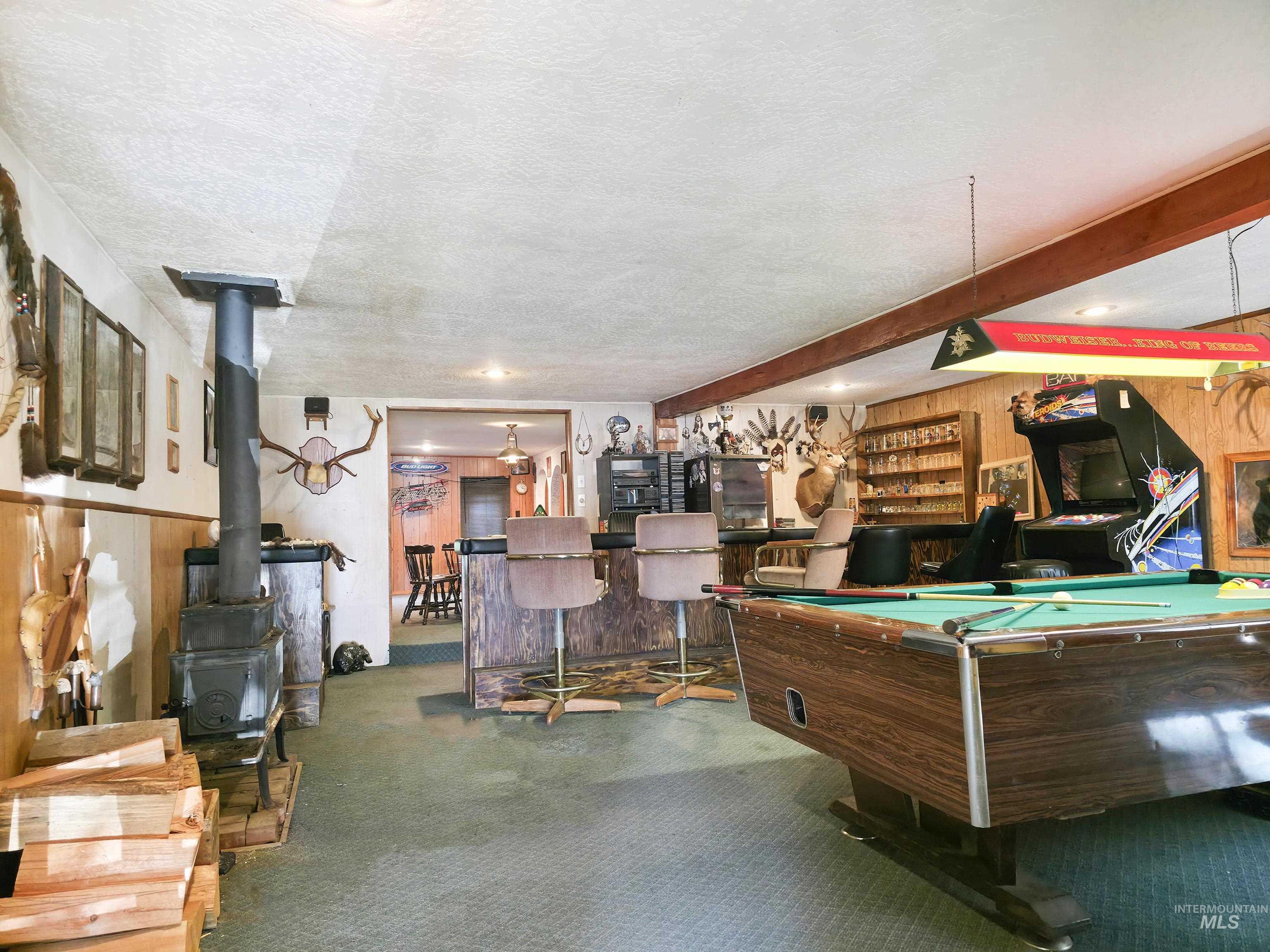 4482 Council Cuprum Road Council, ID 83612 - Photo 23 of 45 Recreation room featuring a wood stove, wood walls, billiards table, carpet, and bar