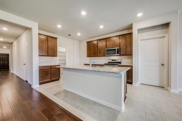 a kitchen with stainless steel appliances a stove top oven a sink a refrigerator and a microwave