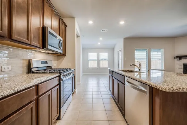 a large kitchen with stainless steel appliances granite countertop a lot of counter space and wooden floor