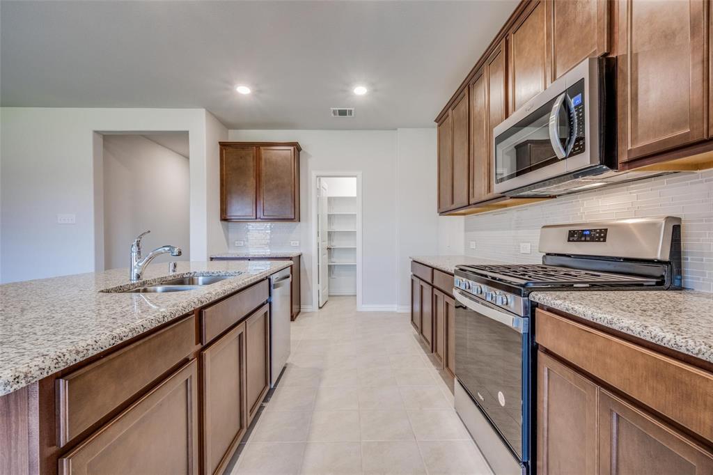 5113 Unity Drive Denton, TX 76207 - Photo 14 of 22 a kitchen with stainless steel appliances granite countertop a stove and a sink