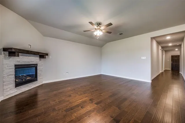 a view of an empty room with wooden floor fireplace and a window