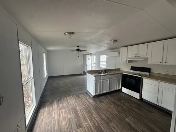a kitchen with granite countertop a stove top oven and cabinets
