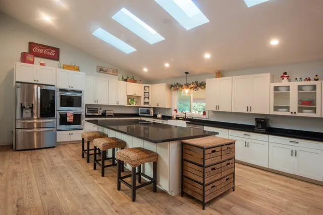 a kitchen with stainless steel appliances granite countertop a table chairs sink and cabinets