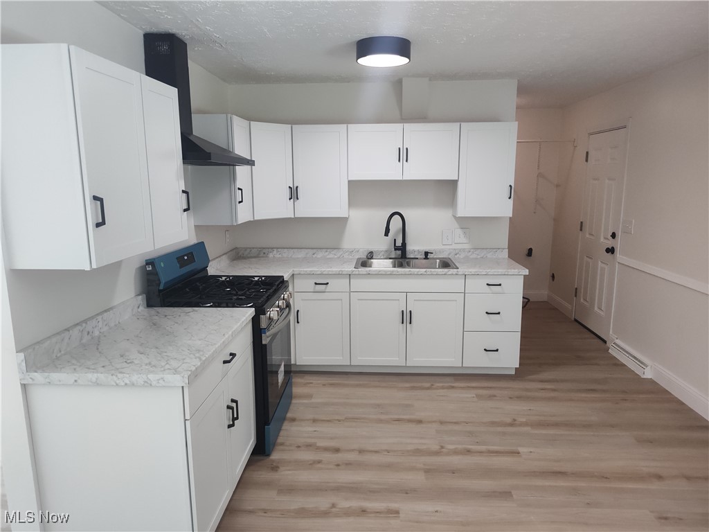 8016 Ninevah Road Geneva, OH 44041 - Photo 21 of 45 Kitchen featuring gas range, light wood-style floors, light countertops, white cabinets, and a textured ceiling