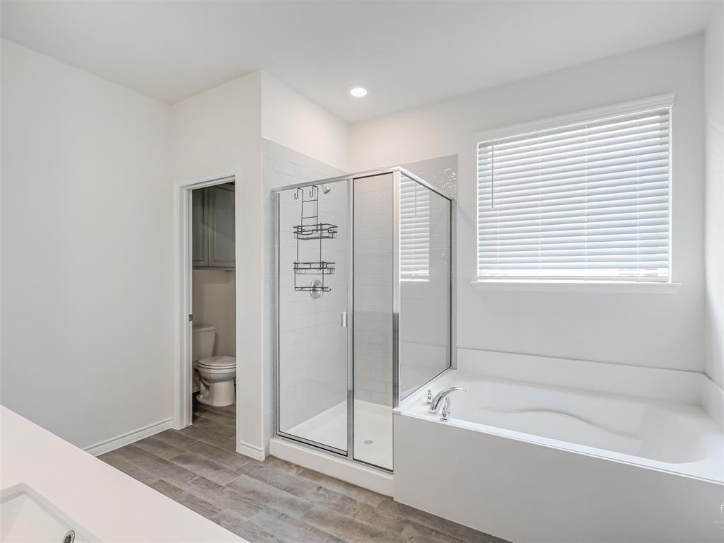 3024 Meredith Lane Forney, TX 75126 - Photo 13 of 29 Bathroom featuring a large soaking tub, separate glass-enclosed shower, wood-finish flooring, and a private water closet