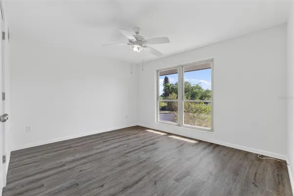 a view of an empty room with wooden floor and a window
