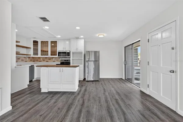 a kitchen with stainless steel appliances kitchen island wooden floors and white cabinets