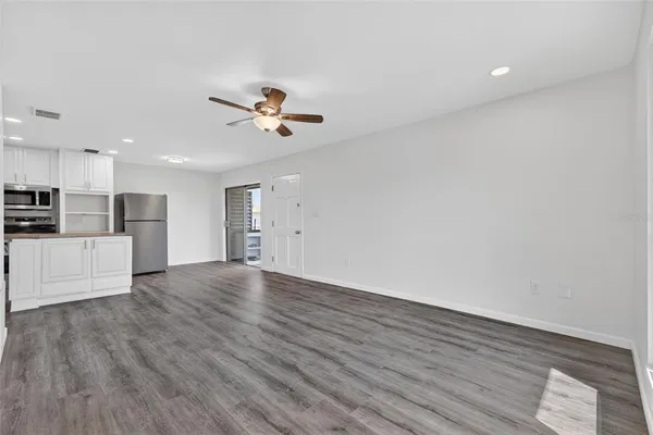 a view of an empty room with a kitchen and wooden floor
