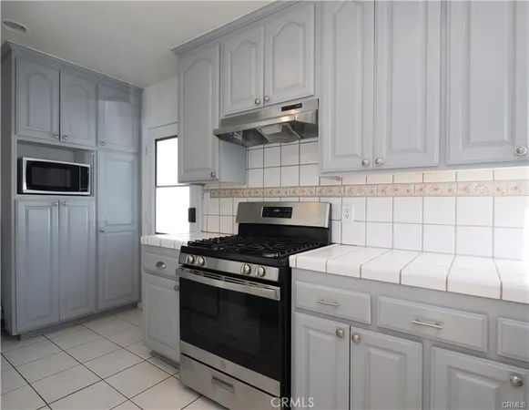 a kitchen with white cabinets and black appliances