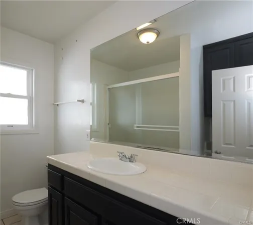 a bathroom with a granite countertop sink a toilet and a mirror