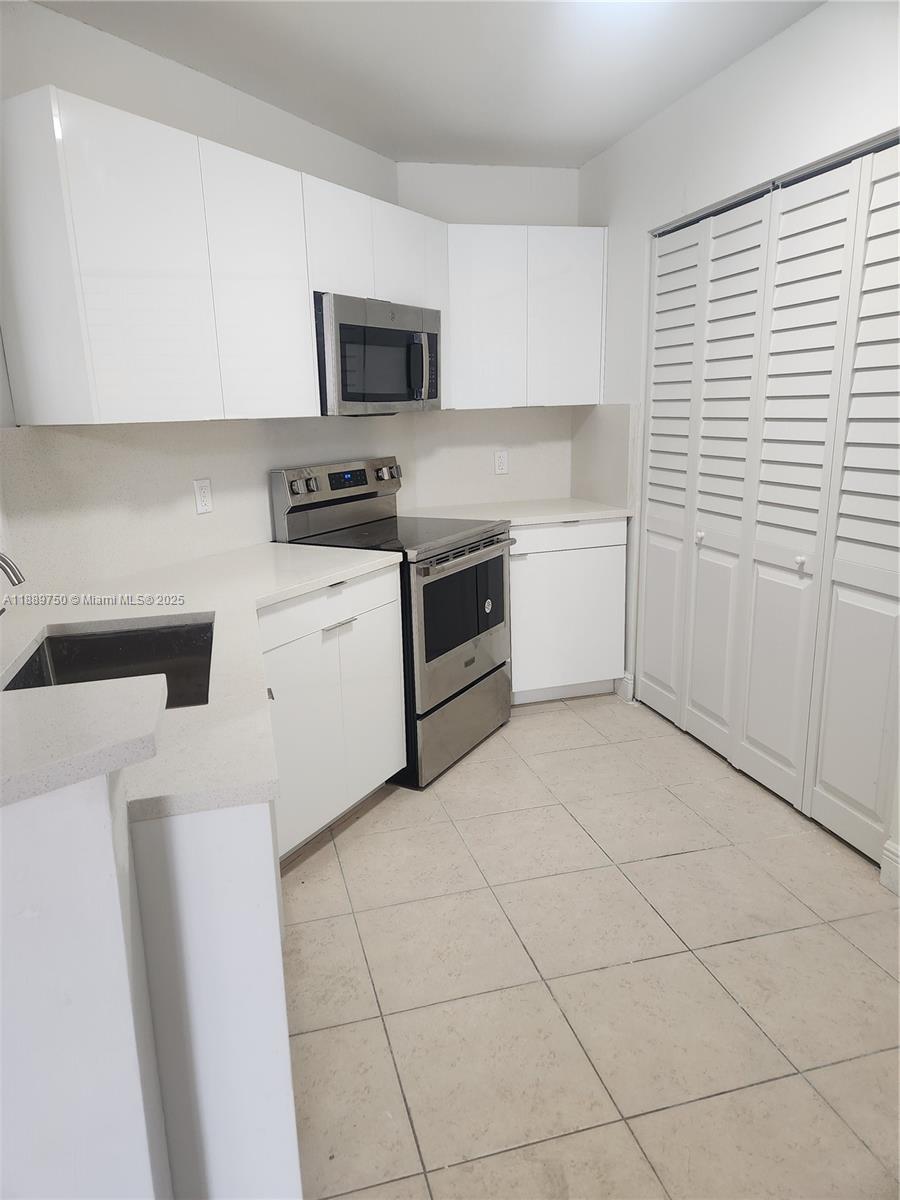 6288 Northwest 186th Street, Unit 201 Hialeah, FL 33015 - Photo 4 of 19 a kitchen with a stove a sink and a microwave