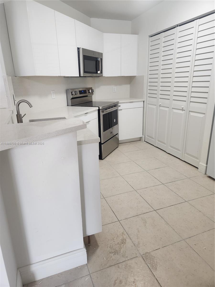 6288 Northwest 186th Street, Unit 201 Hialeah, FL 33015 - Photo 6 of 19 a kitchen with stainless steel appliances a sink a stove a microwave and cabinets