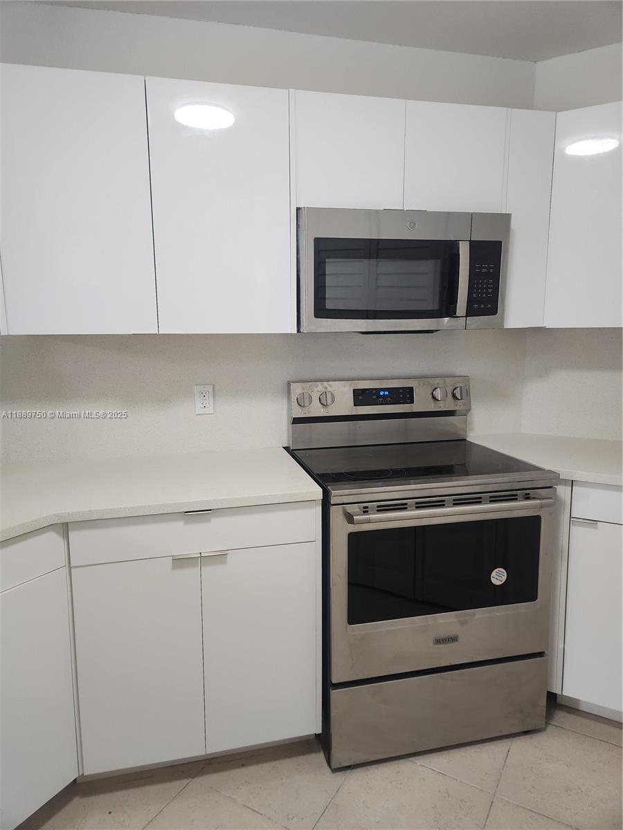 6288 Northwest 186th Street, Unit 201 Hialeah, FL 33015 - Photo 8 of 19 a kitchen with white cabinets and stainless steel appliances