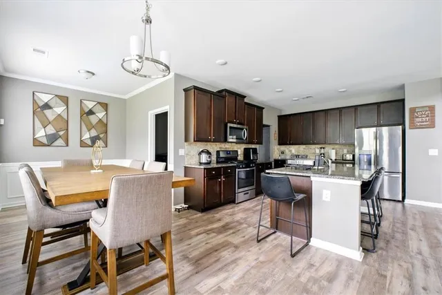 a kitchen with a dining table chairs stainless steel appliances and cabinets