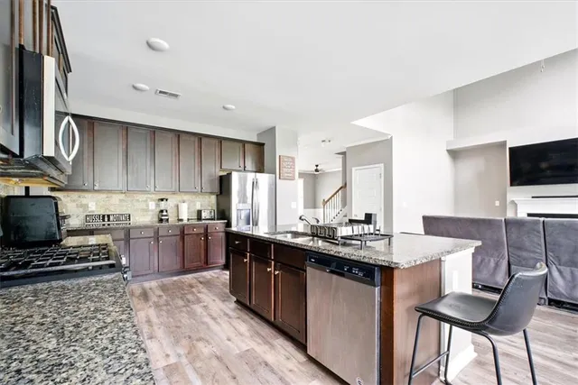 a kitchen with a sink a stove a refrigerator and chairs