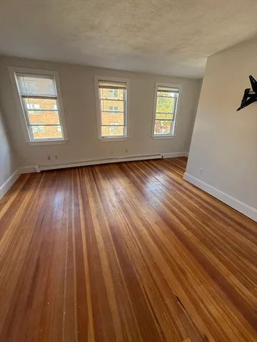 a view of an empty room with wooden floor and window
