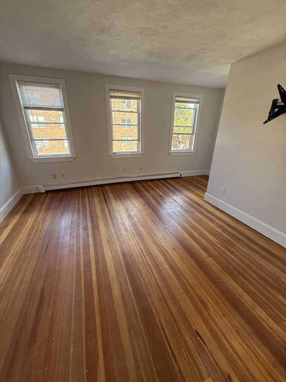 78 Bunker Hill Street, Unit 2 Boston, MA 02129 - Photo 3 of 9 a view of an empty room with wooden floor and window