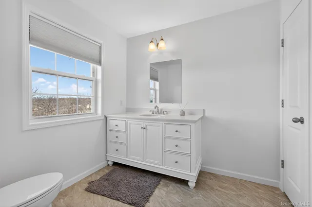 a spacious bathroom with a double vanity sink a toilet and a mirror