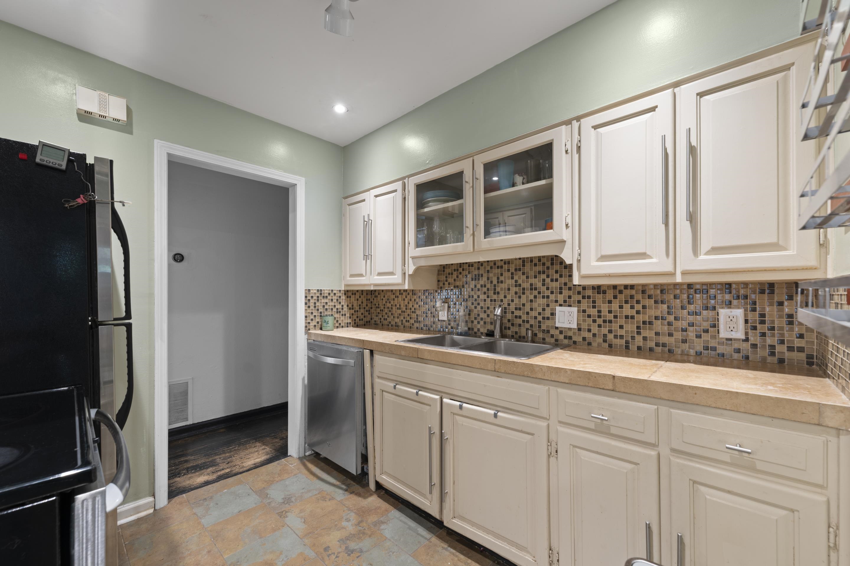 1343 Dearing Road Memphis, TN 38117 - Photo 7 of 19 Kitchen featuring warm-toned cabinetry, a mosaic tile backsplash, double basin sink, and stainless steel dishwasher