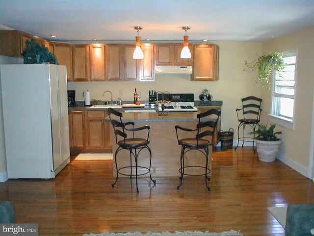 a kitchen with stainless steel appliances granite countertop a stove top oven a sink a dining table and chairs