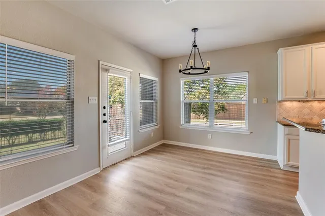 a view of an empty room with window wooden floor and front door