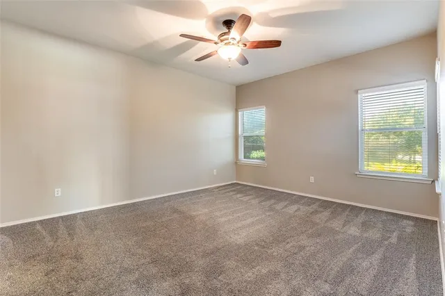an empty room with windows and fan