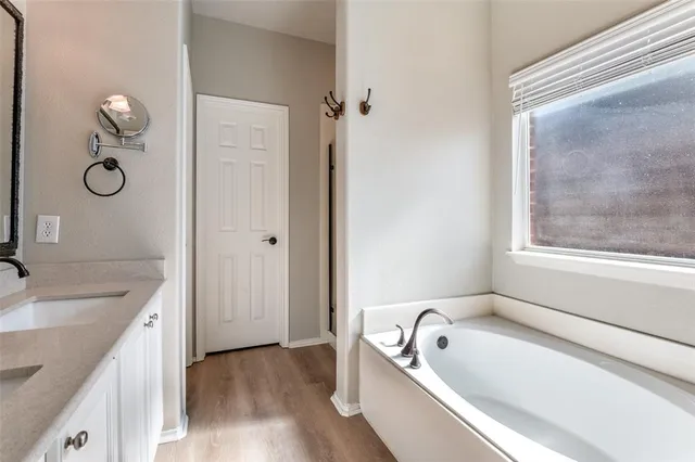 a bathroom with a granite countertop tub a sink and a window