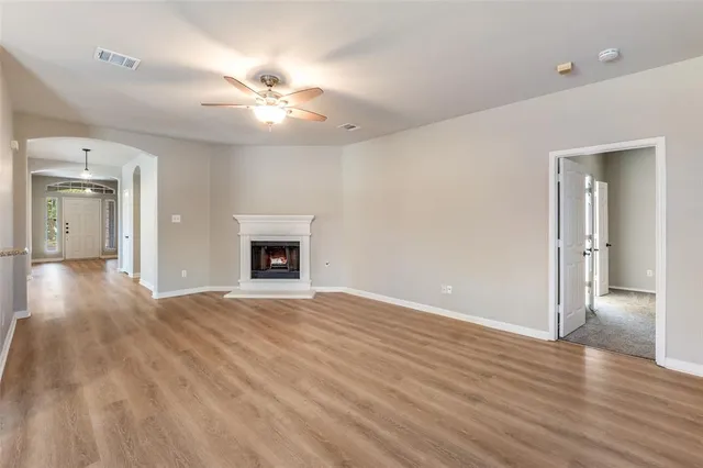 a view of an empty room with wooden floor and a fireplace