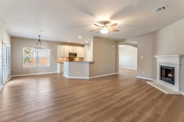 an empty room with wooden floor fireplace and windows