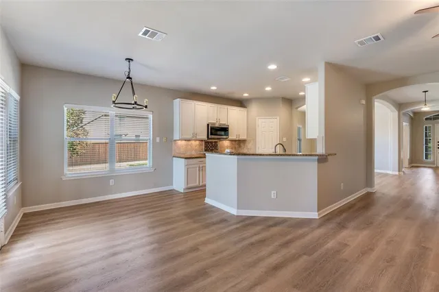 a view of kitchen with kitchen island wooden floor appliances and cabinets