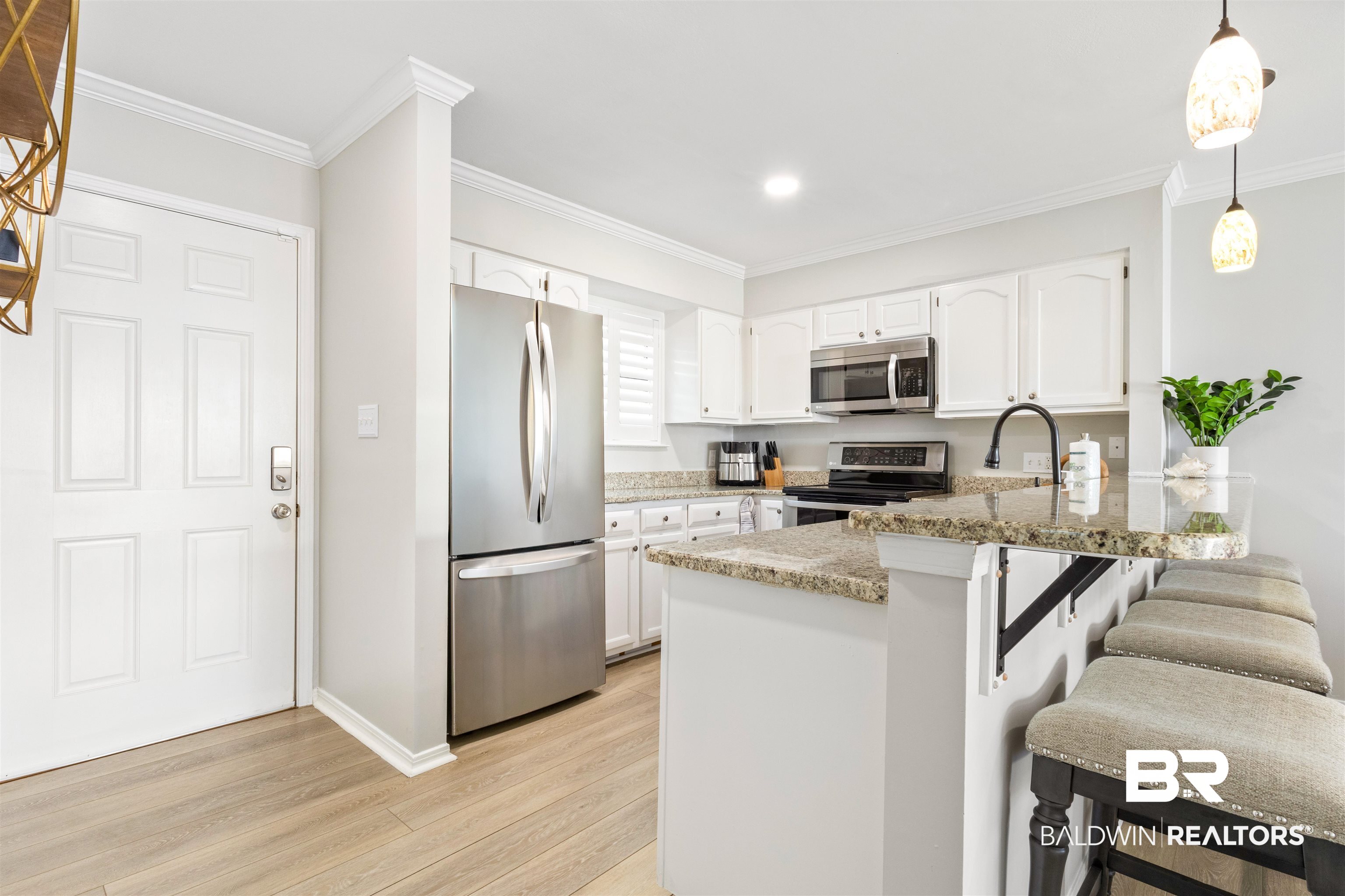 25861 Canal Road, Unit 3 Orange Beach, AL 36561 - Photo 5 of 40 Kitchen featuring hanging light fixtures, white cabinets, stainless steel appliances, a peninsula, and ornamental molding