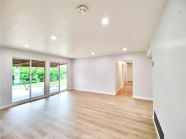 a view of a hallway with wooden floor and a bathroom