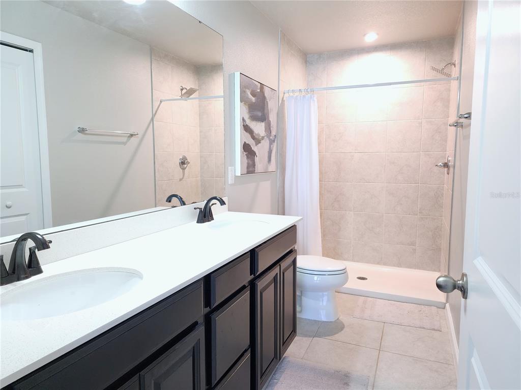 2945 Rambler Ivy Loop Brandon, FL 33510 - Photo 11 of 14 a bathroom with a sink a toilet a mirror and shower