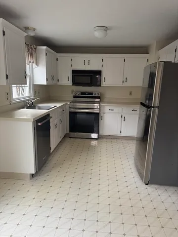 a kitchen with granite countertop a stove a sink and a refrigerator