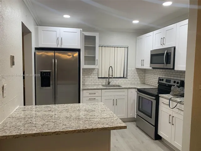 a kitchen with stainless steel appliances granite countertop a refrigerator stove microwave and sink