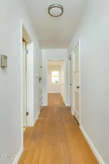 a view of a hallway with wooden floor and a bathroom