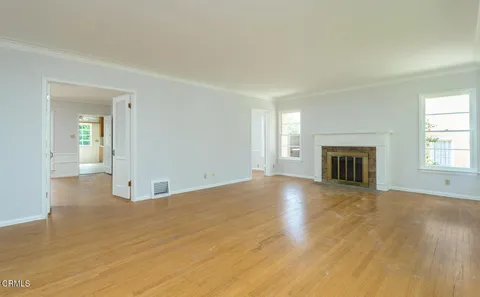 an empty room with windows and fireplace