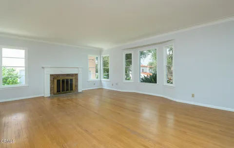 an empty room with windows and fireplace