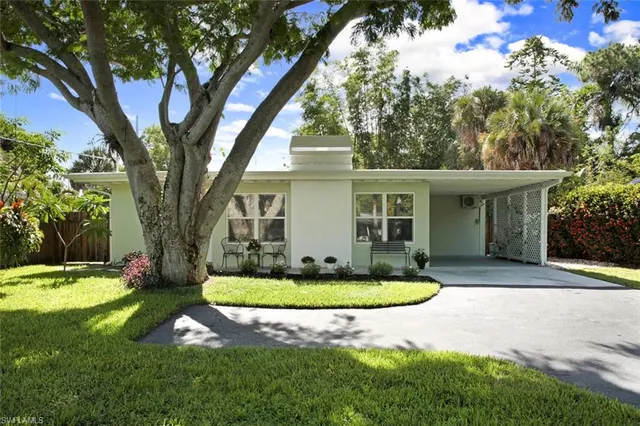 a view of house with a big yard and large trees
