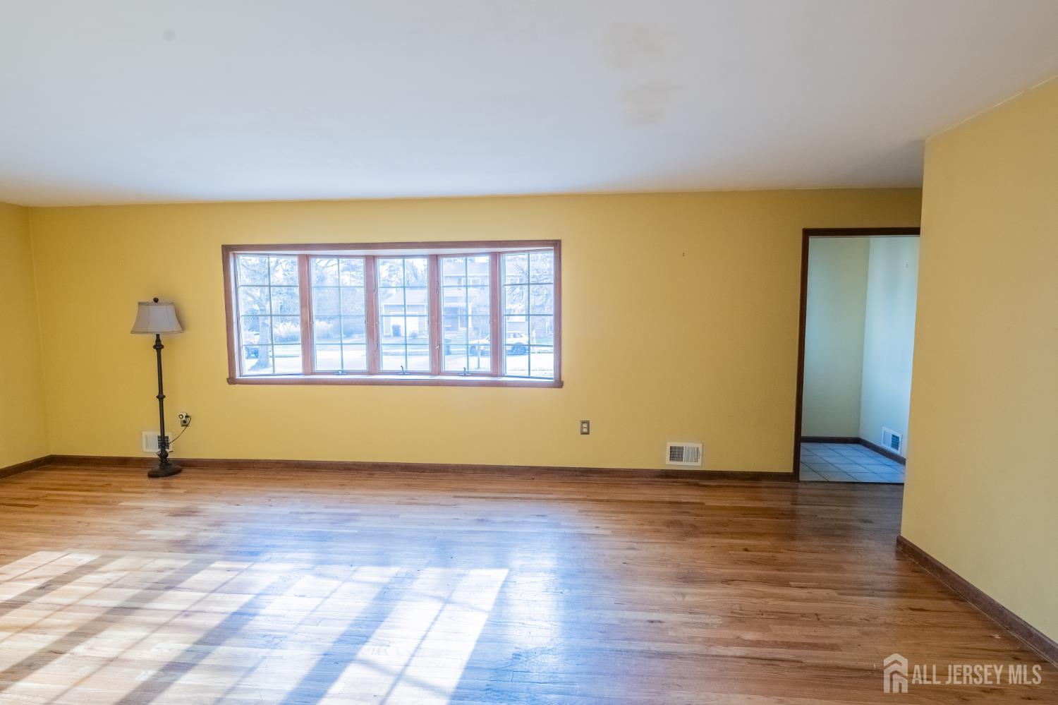 12 Francis Road East Brunswick, NJ 08816 - Photo 5 of 66 a view of an empty room with wooden floor and a window