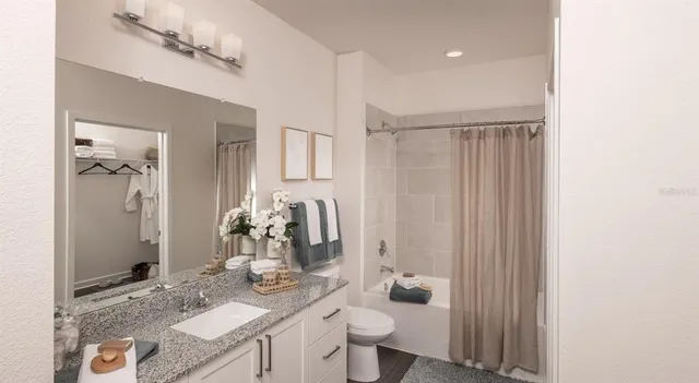 a bathroom with a granite countertop sink a toilet and shower