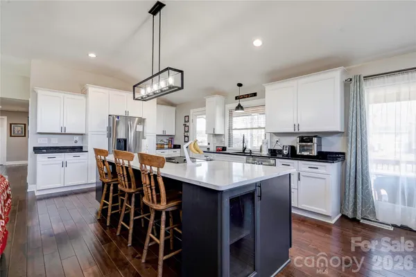 a kitchen with stainless steel appliances granite countertop a sink a stove a refrigerator and island with wooden floor